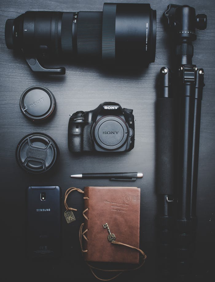 black-sony-dslr-camera-with-telephoto-lens-and-tripod-1447264 Flat lay of photography equipment including a DSLR, lenses, and accessories on a table.