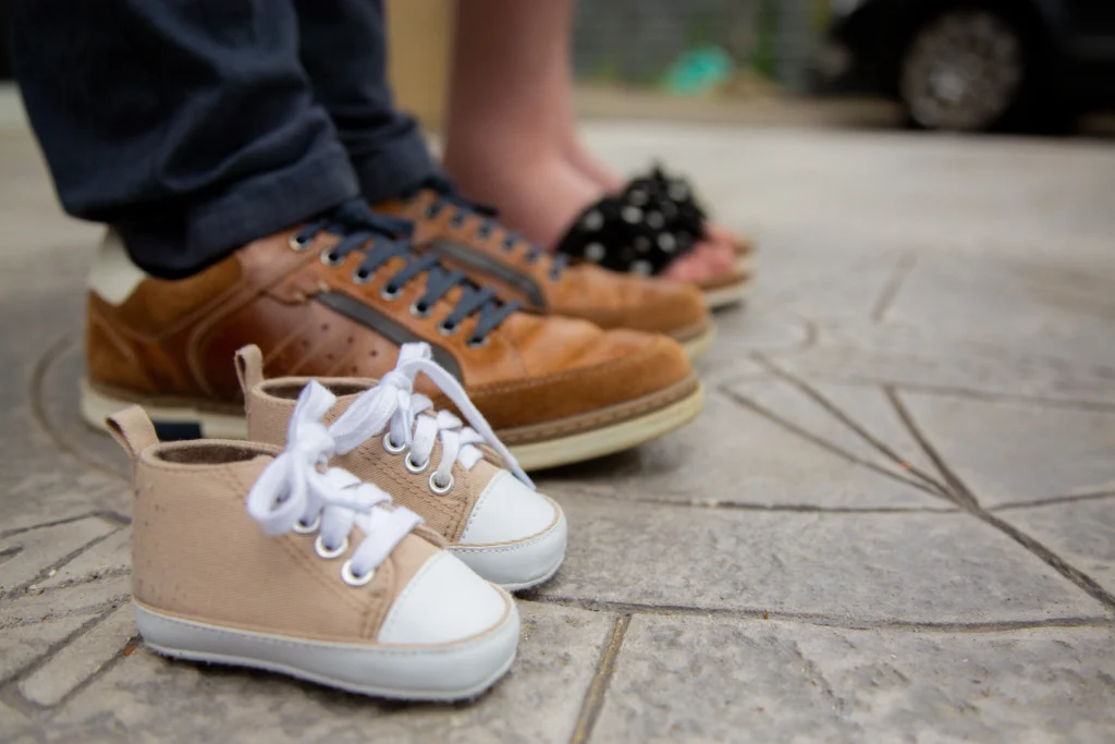 Photo grossesse symbolique avec des chaussures de bébé posées devant les parents