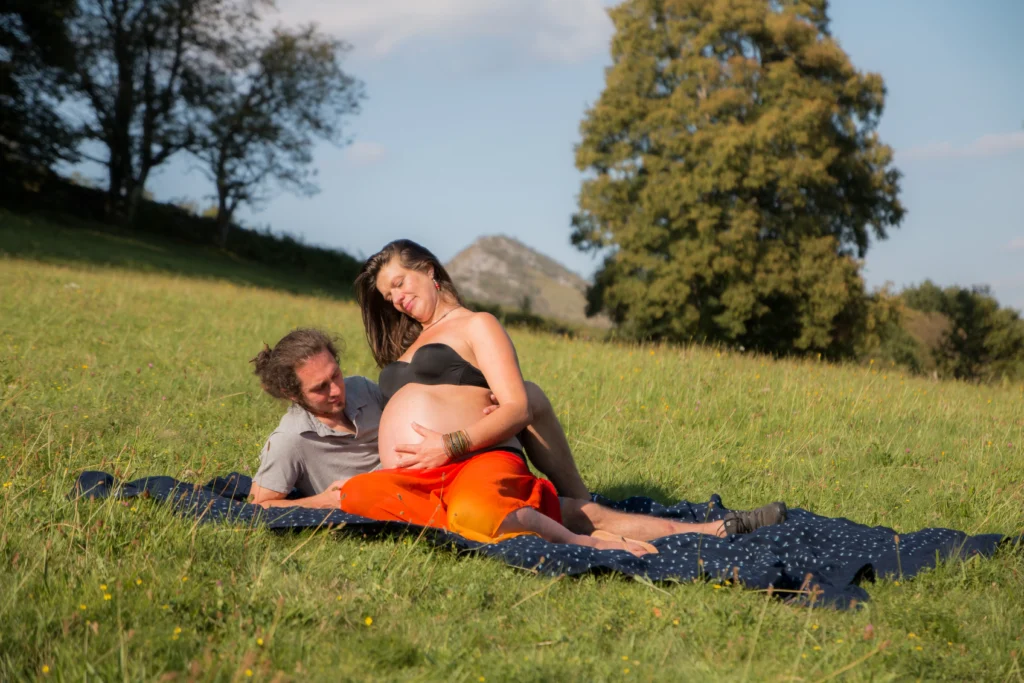 Séance photo grossesse en extérieur dans les Hautes-Pyrénées, un couple partage un moment tendre en pleine nature
