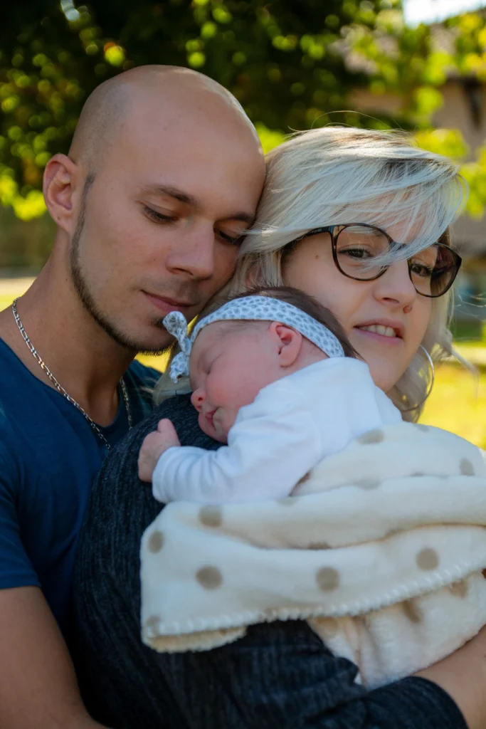 Photo de naissance en famille avec un bébé endormi dans les bras de ses parents à Louey, réalisée par LS Productions photographe naissance