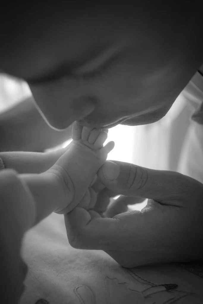 Photo de naissance d’un papa embrassant le pied de son bébé à Juillan, réalisée par LS Productions photographe naissance