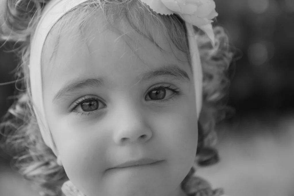 Portrait en noir et blanc d’une petite fille regardant l’objectif à Pouzac, réalisé par LS Productions photographe enfant et famille